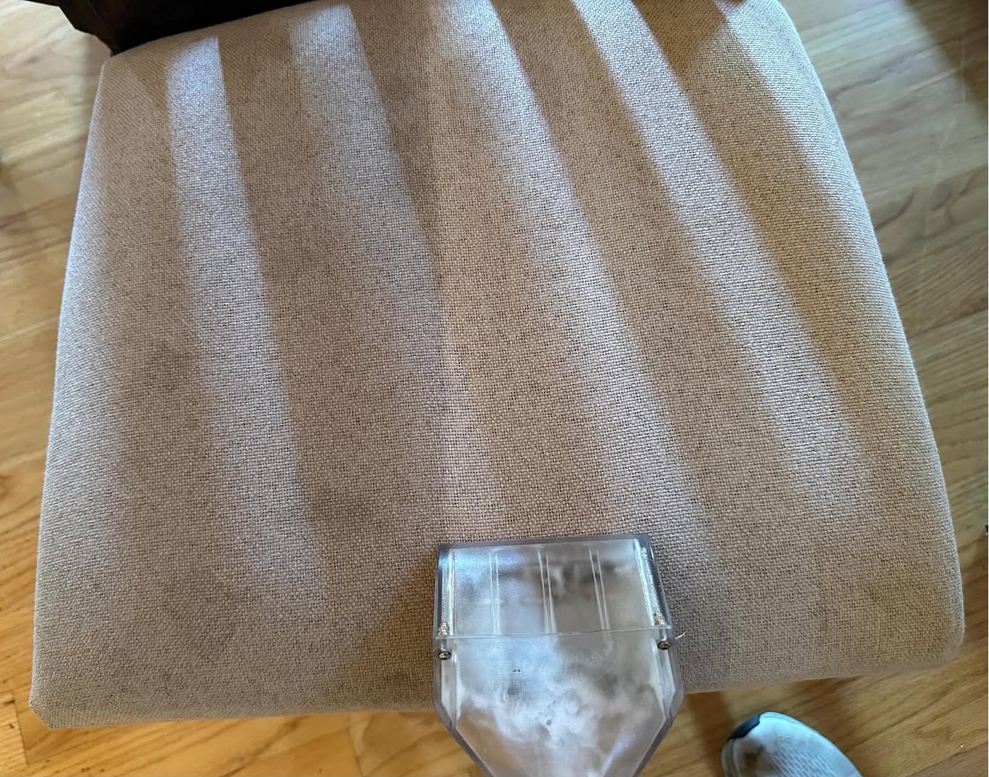 Hot-water extraction cleaning leaving crisp, freshly cleaned stripes across a fabric cushion
